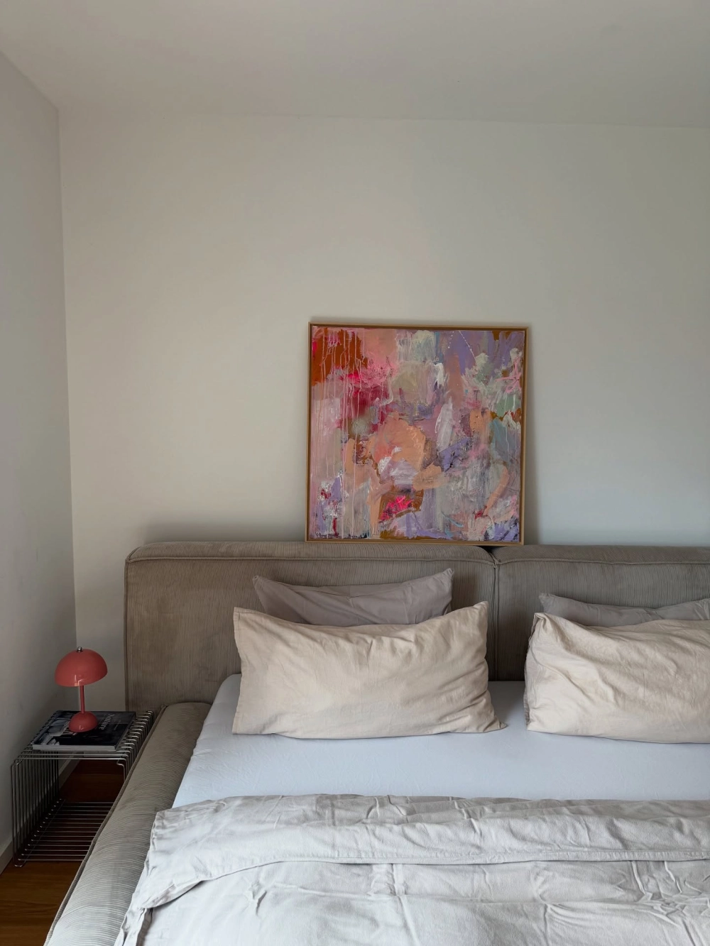 Bức tranh trừu tượng gam màu nóng và đèn ngủ màu đỏ làm điểm nhấn cho màu sơn phòng ngủ trắng tối giản