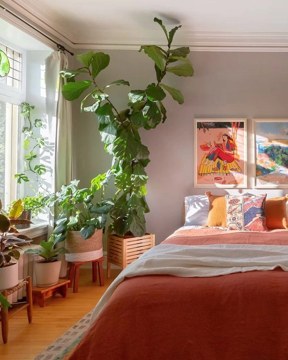 Không gian thoáng đãng ngập nắng với màu sơn phòng ngủ xám nhạt phối cùng cây bàng sing lớn và bộ chăn ga màu cam đất