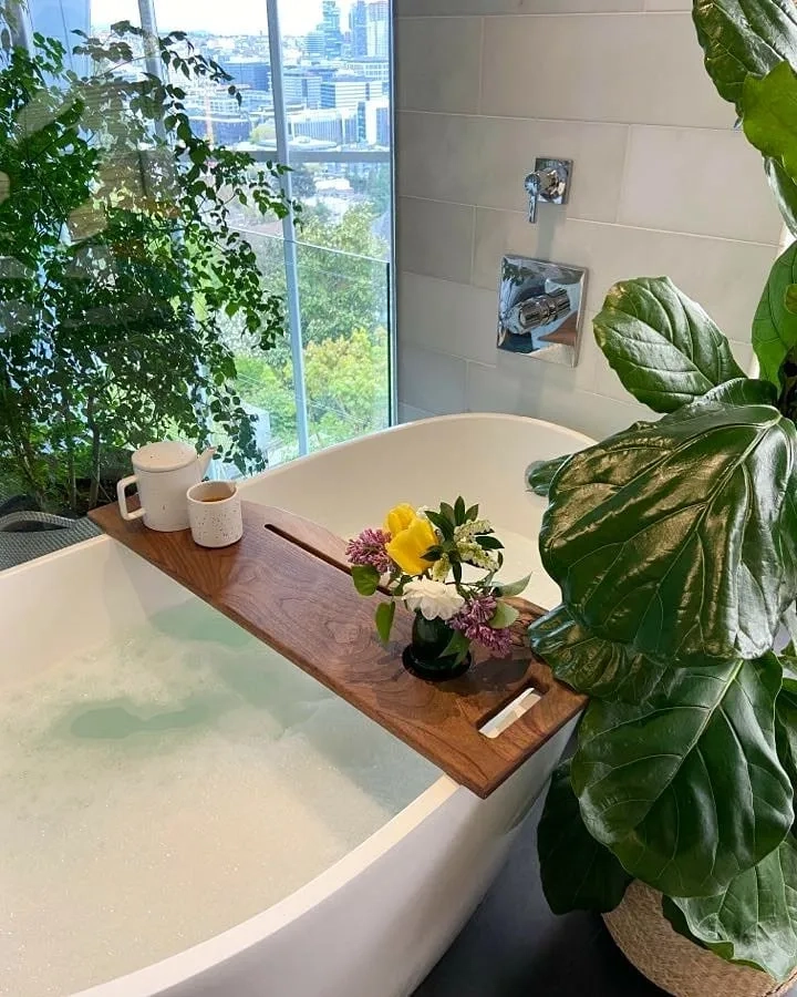 Cây trong nhà tắm đặt cạnh khăn tắm trên nền gạch trắng